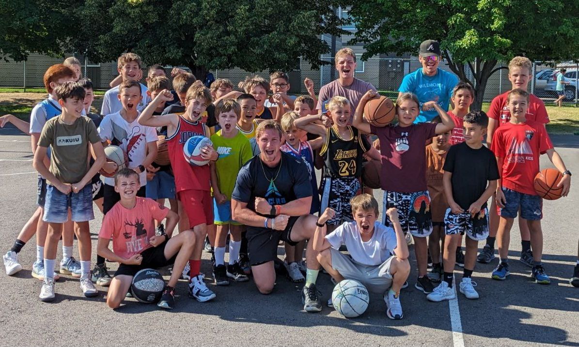 Coach Josh with a group of young basketball players on an outdoor court