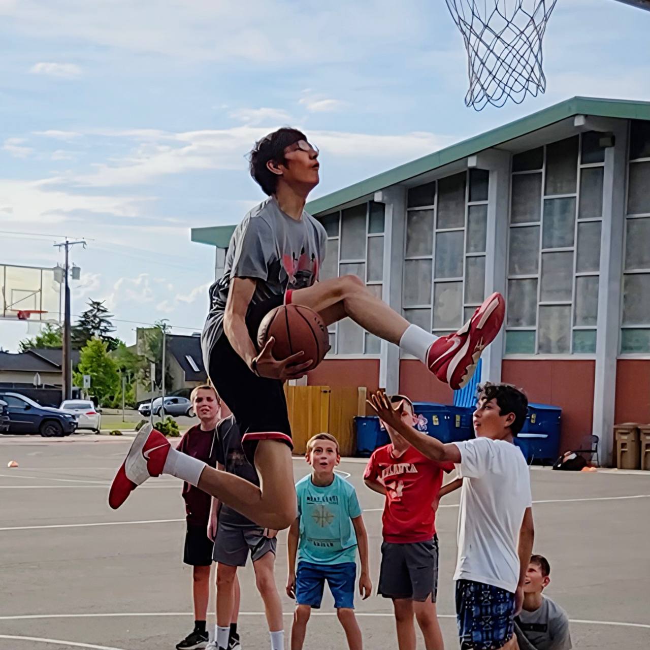 A young basketball player rising toward the hoop while teammates watch